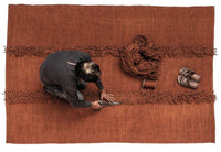 Rustic terracotta rug with textured brown stripes and fringed edges, showcasing handmade craftsmanship.