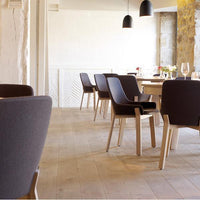 Modern black upholstered dining chairs with natural wood legs, set against a neutral-toned dining room backdrop.