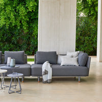 Modern gray sectional sofa with textured cushions, set against lush greenery. Elegant and versatile outdoor design.