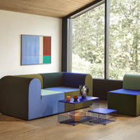 Modern two-toned sofa in blue, green, and purple with geometric patterns, set against a natural light-filled room.