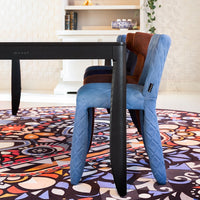 Colorful upholstered chair in blue, brown, and patterned fabric, paired with a vibrant, intricate patterned rug.