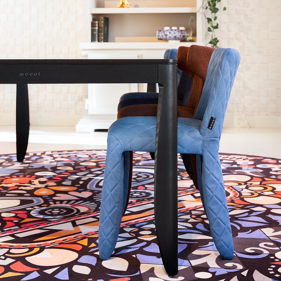 Colorful patterned chair in blue, brown, and black with a geometric rug featuring vibrant swirls and intricate designs.