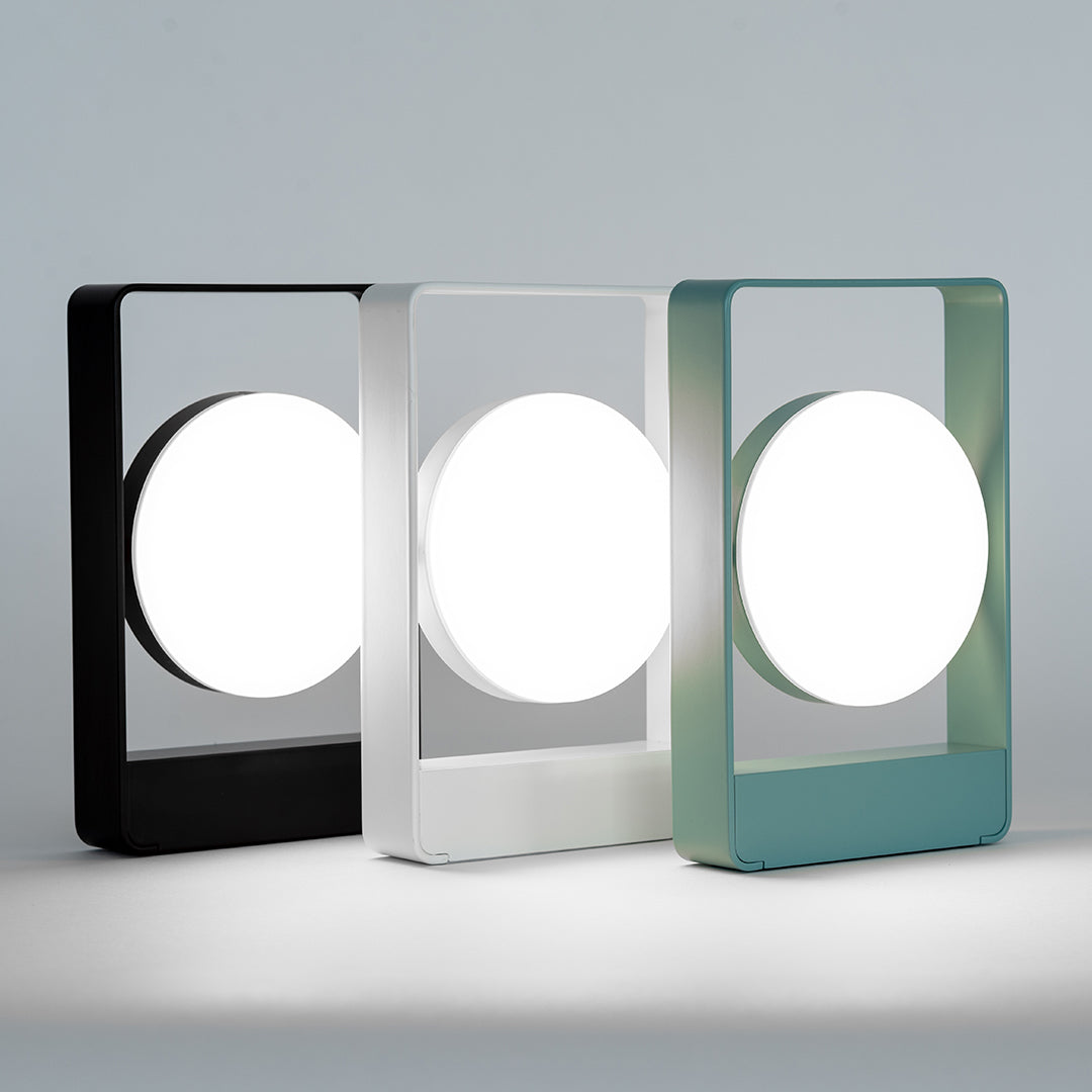Modern lamp trio featuring black, white, and teal frames with circular white shades. Sleek and minimalist design.