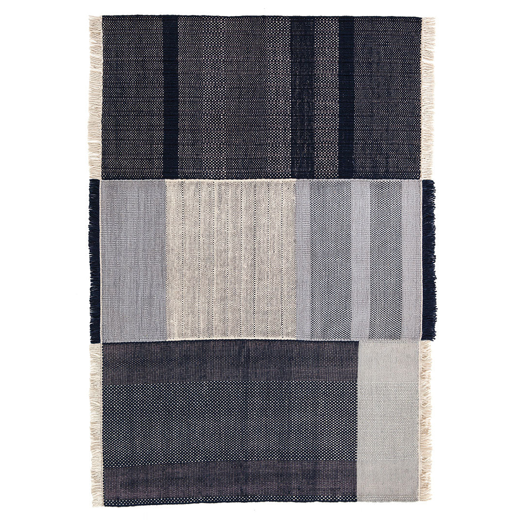 "Textured area rug featuring dark navy, gray, and muted cream stripes in a modern geometric pattern."
