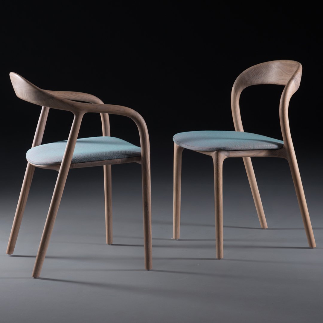 Two modern wooden chairs featuring light blue cushions and a natural wood finish, set against a dark background.