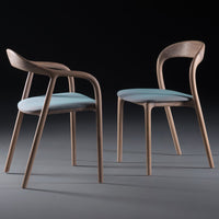 Two modern wooden chairs featuring light blue cushions and a natural wood finish, set against a dark background.