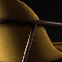 Curved mustard yellow upholstery with dark wood accents against a black background, highlighting modern design and texture.
