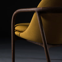 Modern chair featuring a mustard yellow seat and rich wooden frame against a dark background. Stylish and sleek design.
