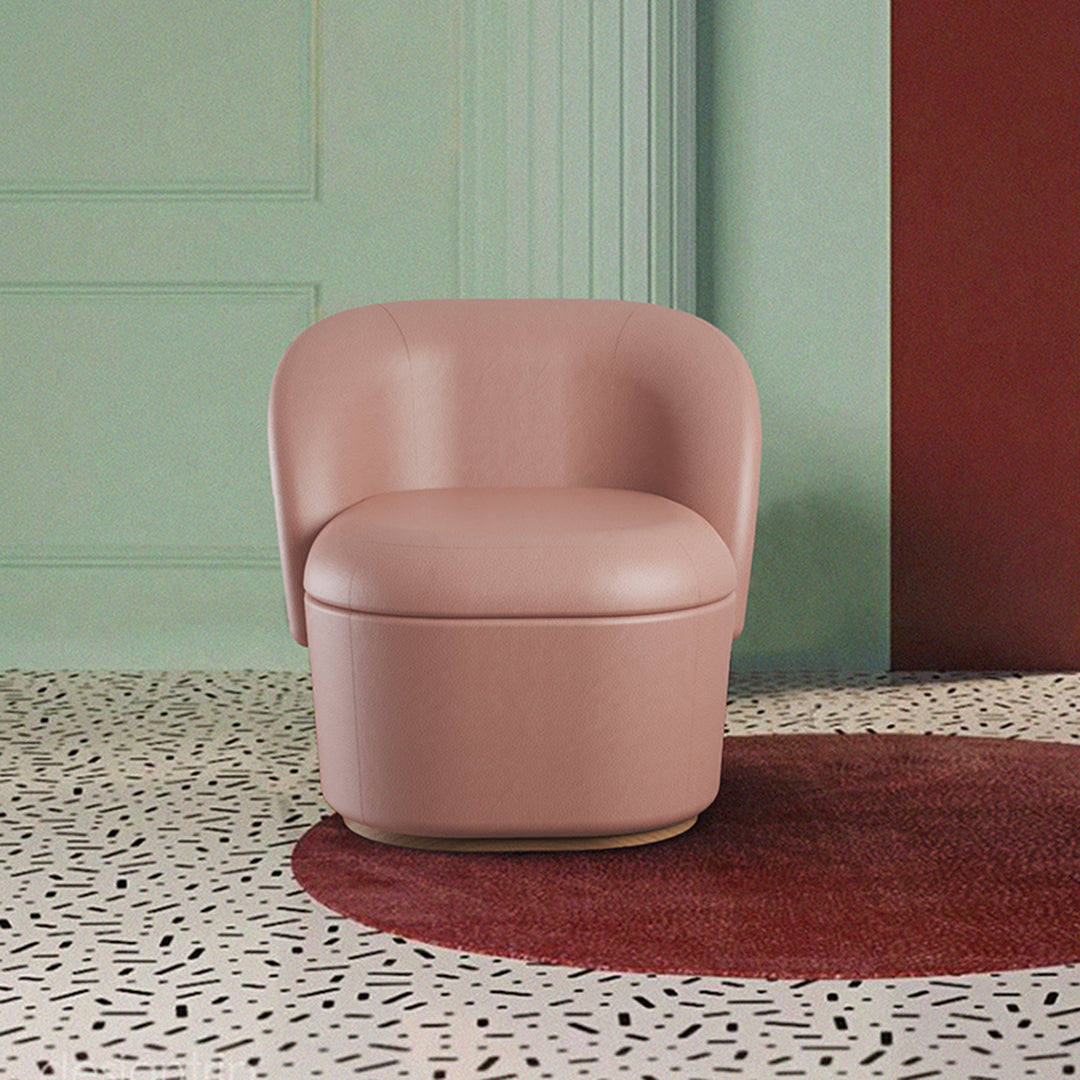 Blush pink chair on a speckled floor with a burgundy circular rug and green wall background. Modern minimalist design.