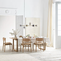 Light wood dining table and chairs with beige upholstery, complemented by white walls and soft neutral decor.