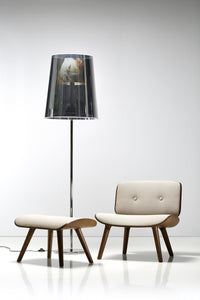 Beige upholstered chair and ottoman with wooden legs, paired with a black transparent lamp featuring a colorful design.