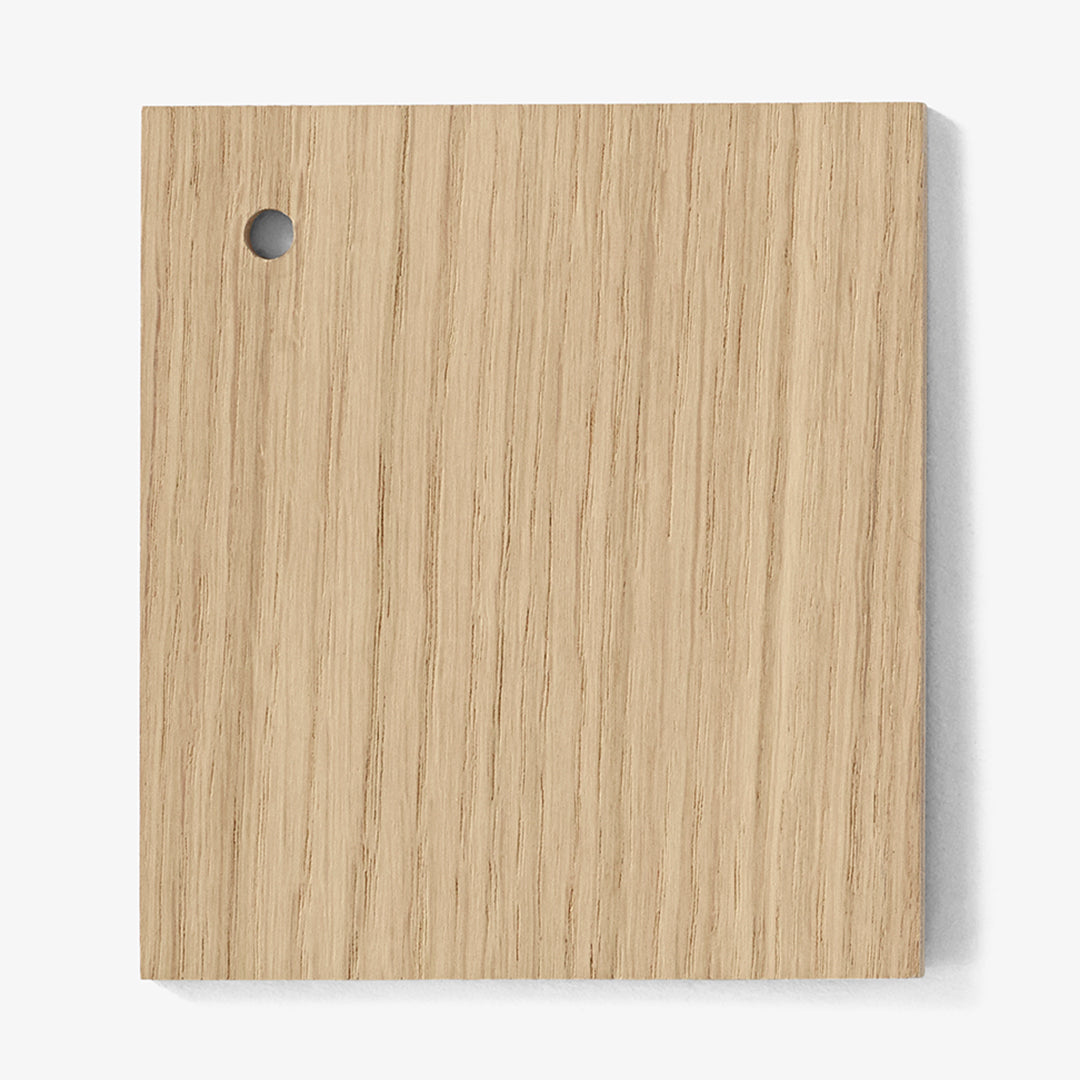 Light oak wood sample with a subtle grain pattern and a small round hole on the corner, showcasing natural textures.