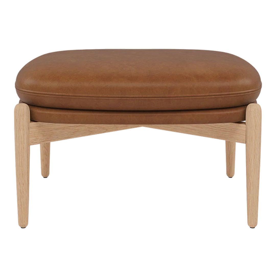 Brown leather ottoman with natural wood legs, featuring a smooth, minimalist design. Perfect for contemporary decor.