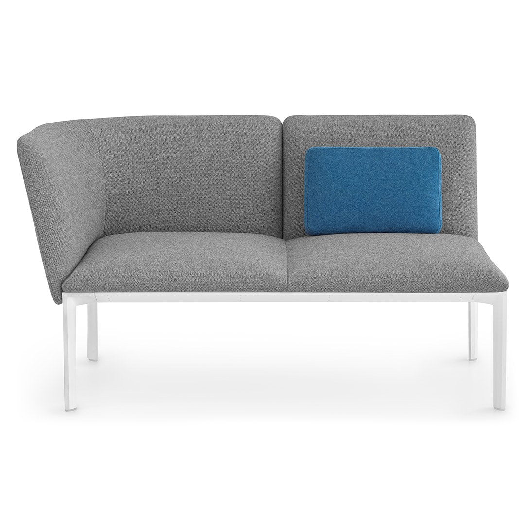 Gray fabric sofa with an asymmetrical design, featuring a blue accent pillow and sleek white legs.