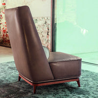 Brown leather accent chair with sleek design and wooden base, set against a textured green and patterned backdrop.