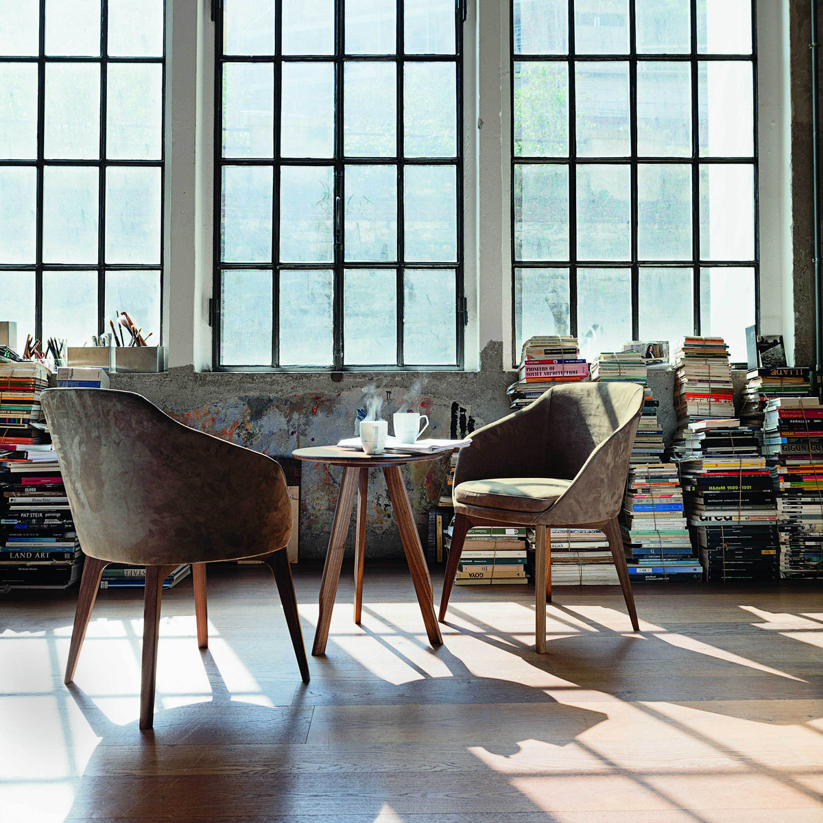 "Contemporary chairs in earthy tones, featuring soft textures, paired with a wooden table in a sunlit room."