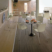 Modern white chairs and black table in an elegant indoor setting with rich wooden flooring and exposed brick wall pattern.