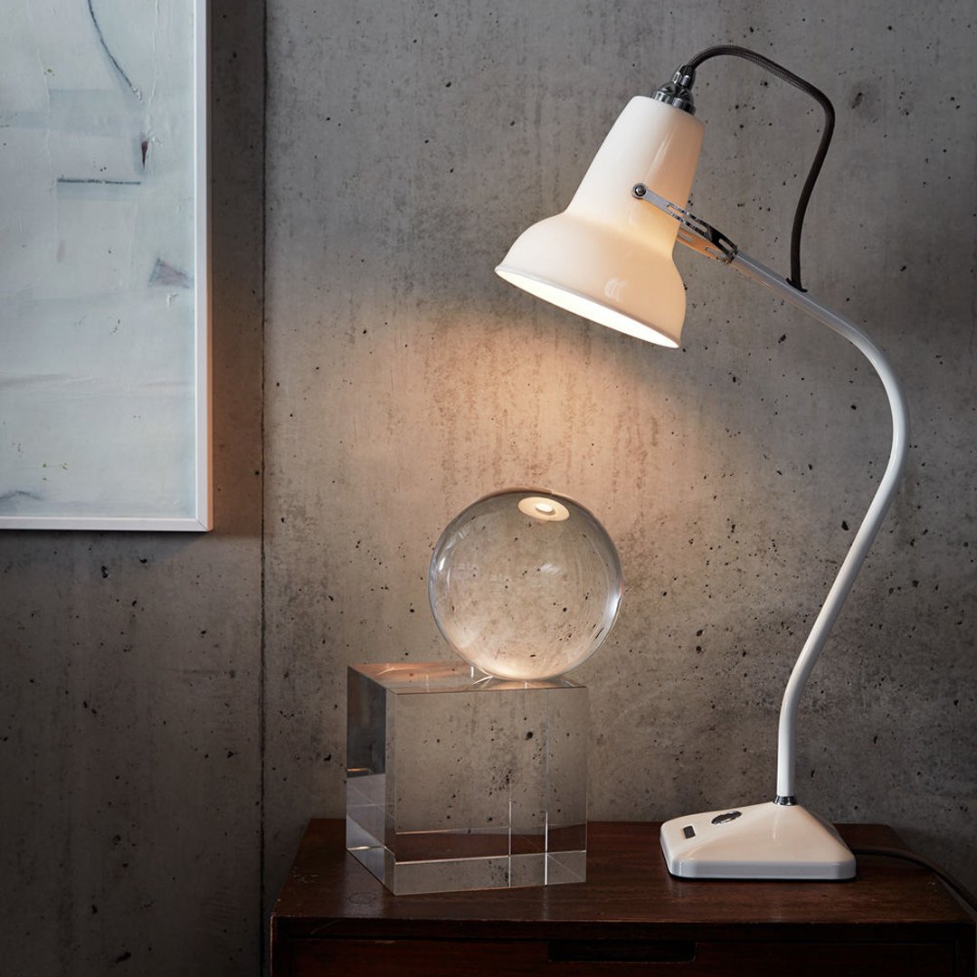 White stylish lamp with curved design, clear glass orb, and concrete background. Simple and modern aesthetic.