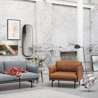 Gray and tan upholstered sofas with a textured throw, set against a minimalist, light-toned interior backdrop.