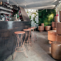 "Stylish bar area featuring black accents, green mosaic wall, and copper-toned stools and seating."