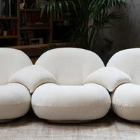 Cream-colored modern three-seater sofa with plush, rounded design and soft texture. Ideal for stylish living spaces.