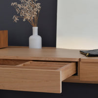 Light oak wood desk with minimalist design, featuring a smooth surface and stylish drawer. Background is dark grey.
