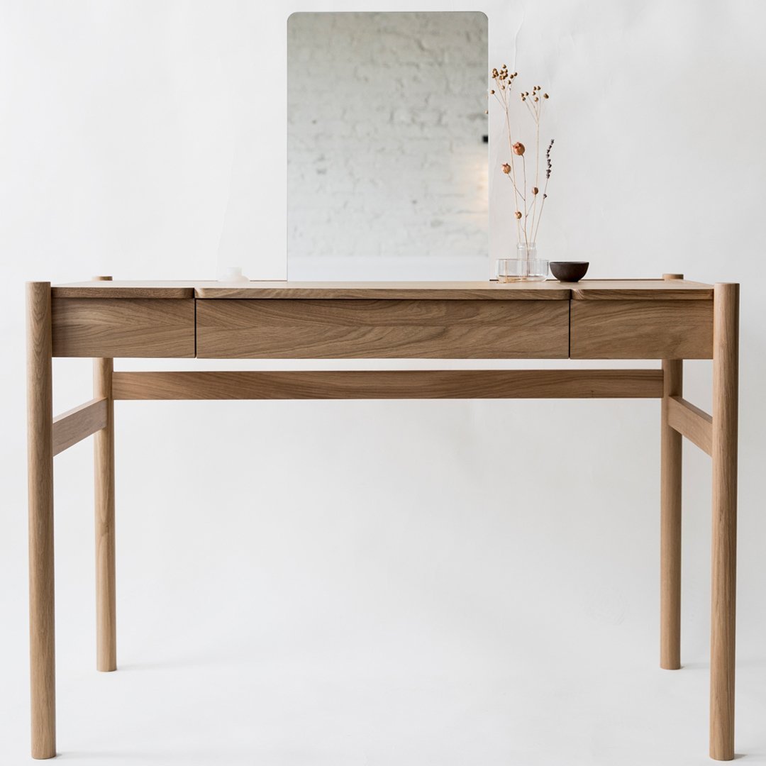 Light wood desk with a natural finish, featuring smooth lines and a minimalist design, paired with a simple reflective mirror.