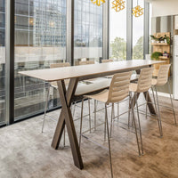 Minimalist white tabletop with natural wood legs, complemented by pale beige chairs on a soft gray carpet.