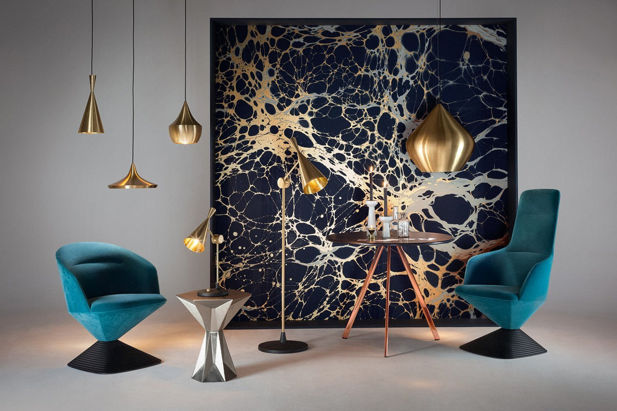 Teal chairs, gold pendant lights, and a navy-blue backdrop with a marbled gold pattern create a modern, elegant setting.