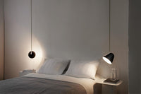 Modern bedroom with white walls, gray bedding, and black pendant lamps for a chic, minimalist look.