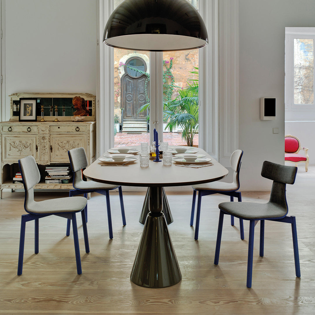 Stylish dining table with a round wooden top and six sleek gray and blue chairs in a modern interior.