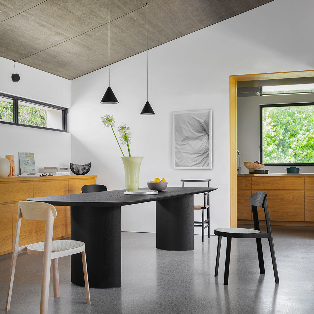 Stylish black round table with sleek chairs, contrasting warm wood tones and neutral gray flooring. Modern minimalist decor.