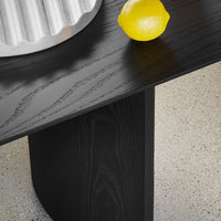 Black wooden table featuring a smooth finish, paired with a silver dish and a vibrant yellow lemon on a light speckled surface.