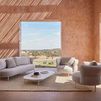 Light gray sofa set against warm terracotta walls, featuring a natural woven rug and soft, muted color palette.