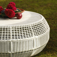 White woven coffee table with circular design, featuring a textured pattern and adorned with red flowers and fruits.