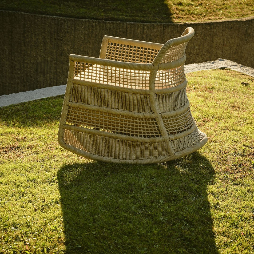 Natural woven rattan chair in a soft beige hue, featuring a unique open pattern and curved design. Perfect for outdoor decor.