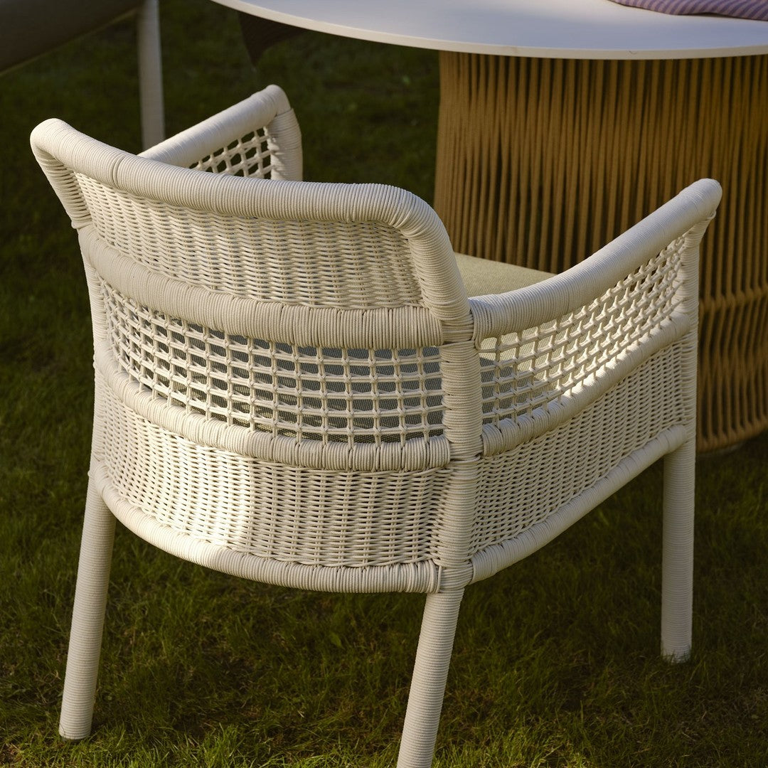 White woven chair with a textured pattern, set against a natural green grass backdrop.