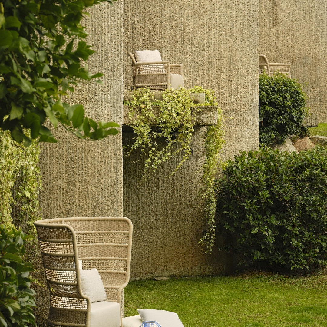 "Textured beige wall with greenery and light-colored outdoor chairs for a natural, calming vibe."
