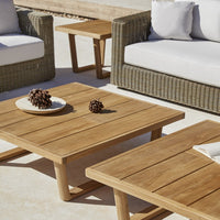 Natural wood grain coffee tables with a warm brown finish, paired with neutral-colored cushions in a cozy outdoor setting.
