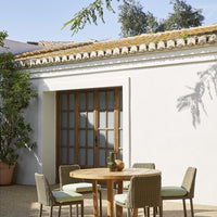 "Light green and beige outdoor dining set against a white wall with natural sunlight."