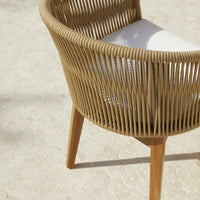 Natural beige woven chair with light wood legs and a white cushion, featuring a contemporary curved design.