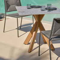 "Gray outdoor dining set with a light wood base and a textured tabletop, set against a turquoise background."