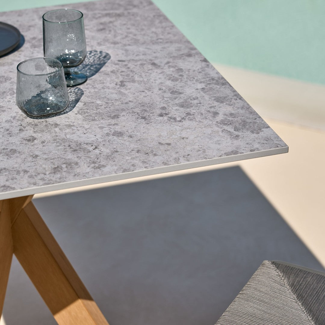 Gray textured tabletop with wooden legs, complemented by clear glassware and a subtle background color.