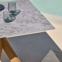 Gray textured tabletop with wooden legs, complemented by clear glassware and a subtle background color.
