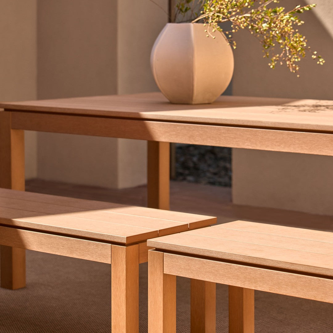 Light wooden table and benches with smooth surfaces, complemented by a soft beige vase and natural textures.