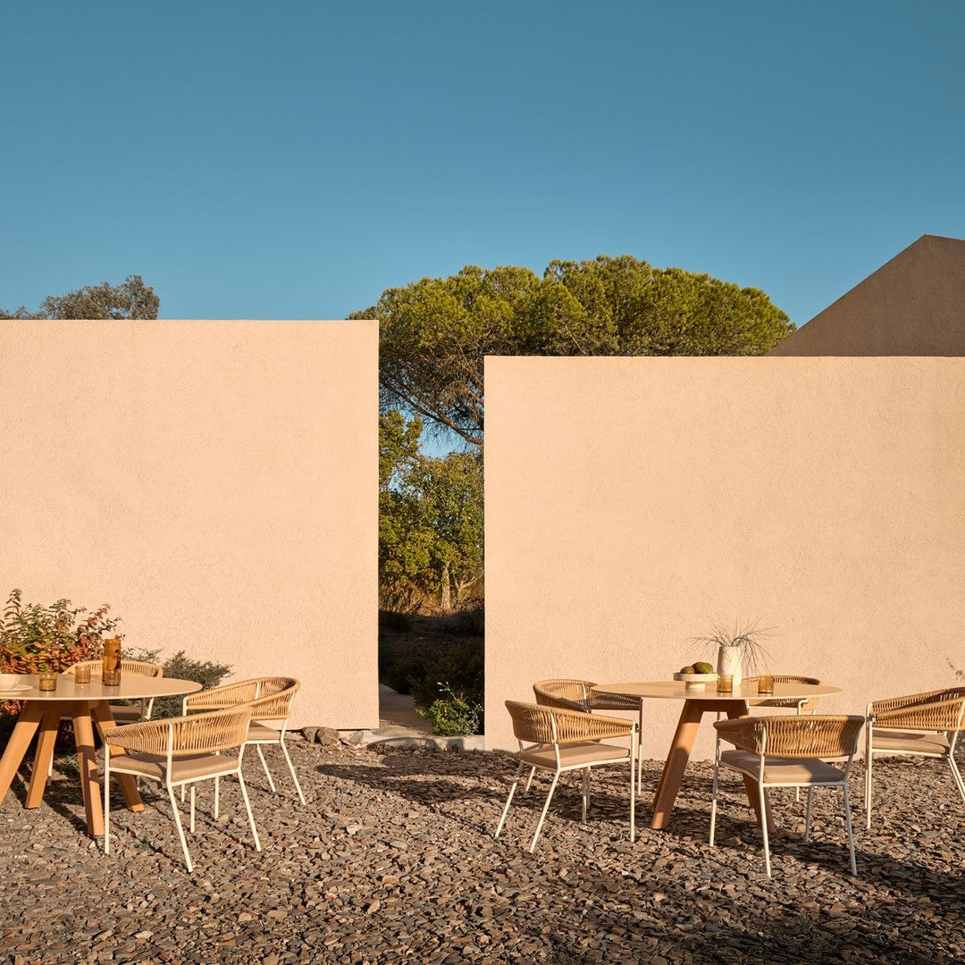 "Neutral beige walls with wooden outdoor furniture; warm earthy tones and natural textures create a serene atmosphere."