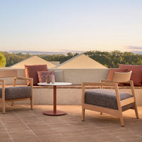 "Outdoor seating set with beige wooden frames, gray fabric cushions, and rust-orange accent pillows on a tiled patio."