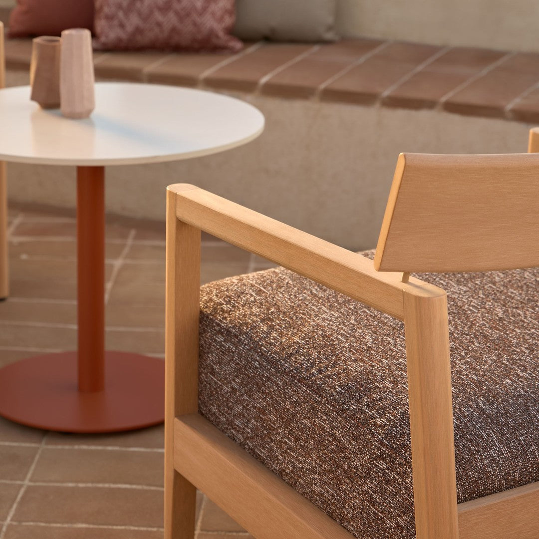 Light wood chair with textured brown cushion, white round table, and a red base, featuring a warm, minimalist aesthetic.
