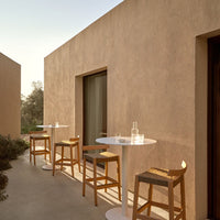 "Elegant beige walls with wood and white accents, featuring minimalist outdoor bar stools and tables."