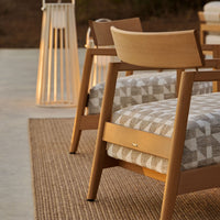 Wooden chair with a geometric gray and white patterned cushion, complemented by a natural woven rug.